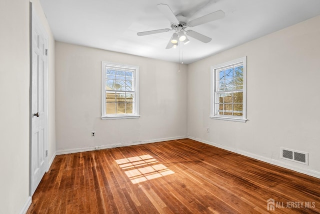 spare room featuring visible vents, ceiling fan, baseboards, and wood finished floors