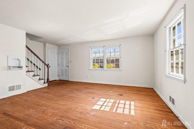 empty room featuring visible vents, stairway, and wood finished floors