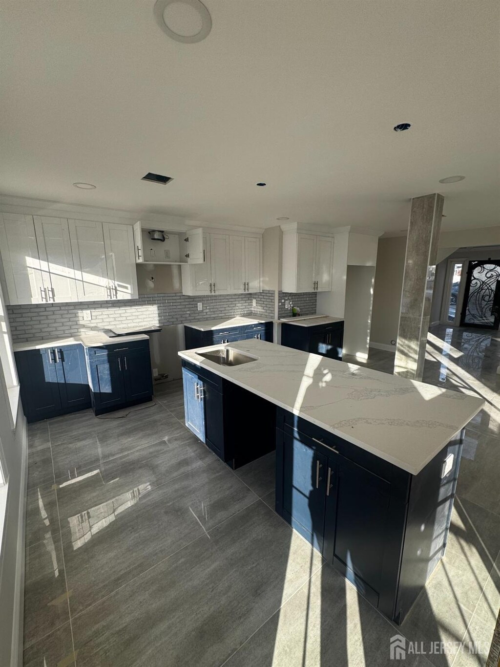 kitchen with light stone countertops, sink, a kitchen island, and white cabinets