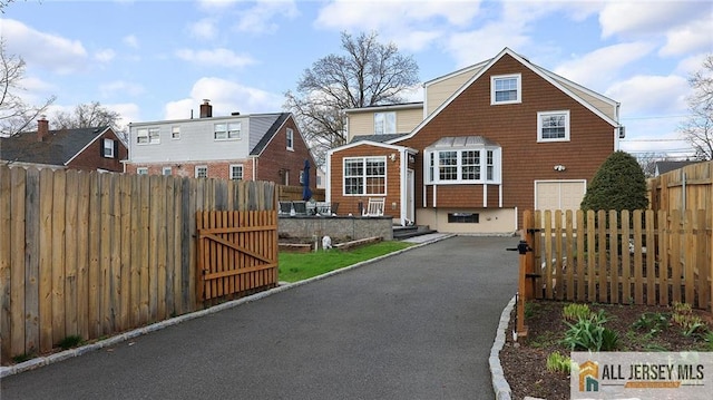 view of front facade featuring entry steps, fence, a gate, and driveway