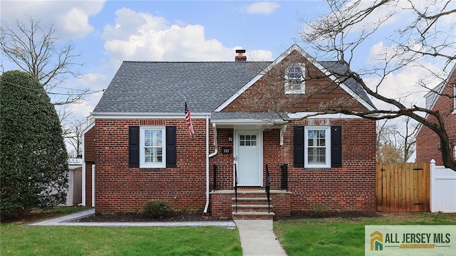view of front of property featuring a chimney, fence, brick siding, a gate, and roof with shingles