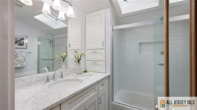 bathroom with vaulted ceiling with skylight, vanity, and combined bath / shower with glass door