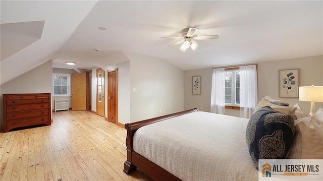 bedroom featuring baseboards, vaulted ceiling, light wood-style flooring, radiator, and ceiling fan