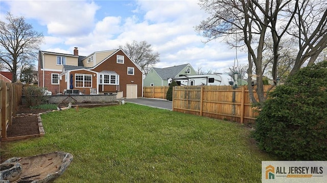 back of property featuring a yard, a fenced backyard, a patio area, a chimney, and driveway