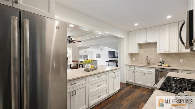 kitchen with dark wood-style flooring, white cabinetry, freestanding refrigerator, ceiling fan, and a sink