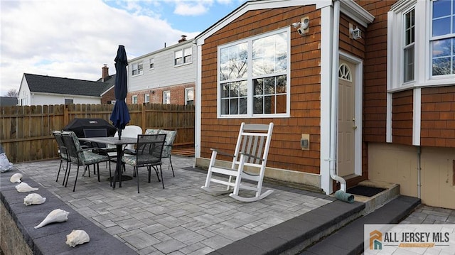 view of patio with outdoor dining space, entry steps, and fence