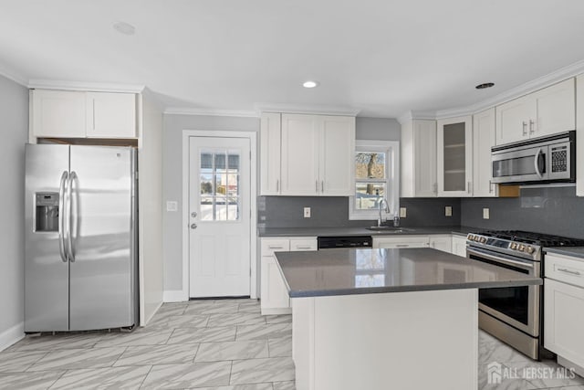 kitchen featuring sink, white cabinetry, tasteful backsplash, a center island, and appliances with stainless steel finishes