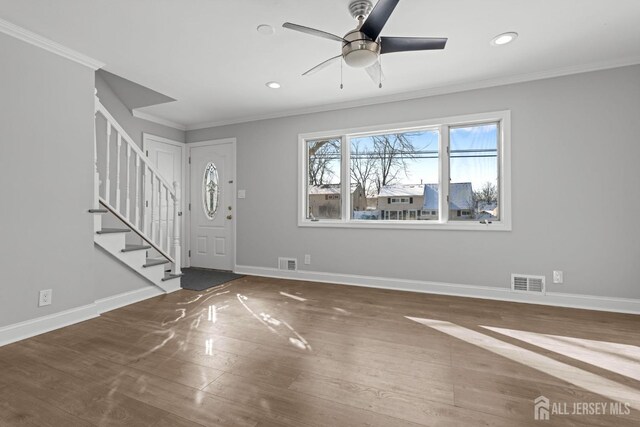 entryway with wood-type flooring, ornamental molding, and ceiling fan