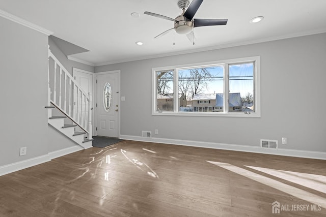 entrance foyer featuring baseboards, visible vents, stairway, wood finished floors, and crown molding