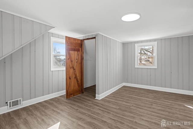 additional living space featuring a wealth of natural light, wood finished floors, visible vents, and baseboards