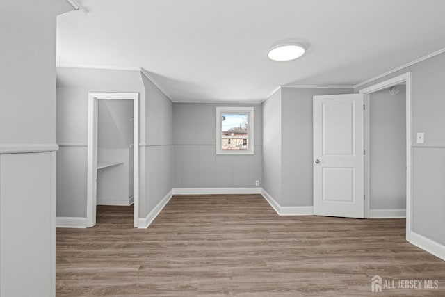 additional living space with baseboards and wood finished floors