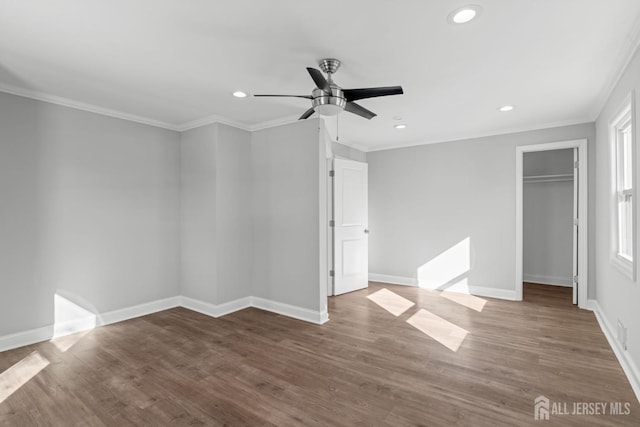 unfurnished bedroom with ceiling fan, hardwood / wood-style floors, ornamental molding, a spacious closet, and a closet