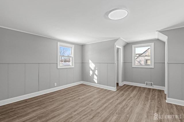 bonus room with a wainscoted wall, visible vents, plenty of natural light, and wood finished floors