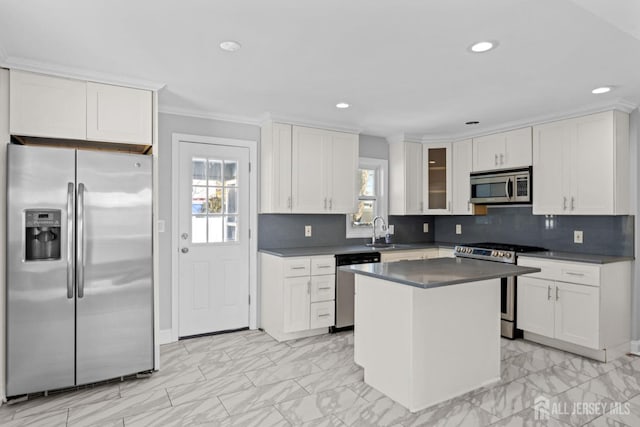 kitchen with a kitchen island, white cabinetry, appliances with stainless steel finishes, dark countertops, and glass insert cabinets