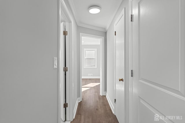 corridor featuring baseboards, dark wood finished floors, and crown molding