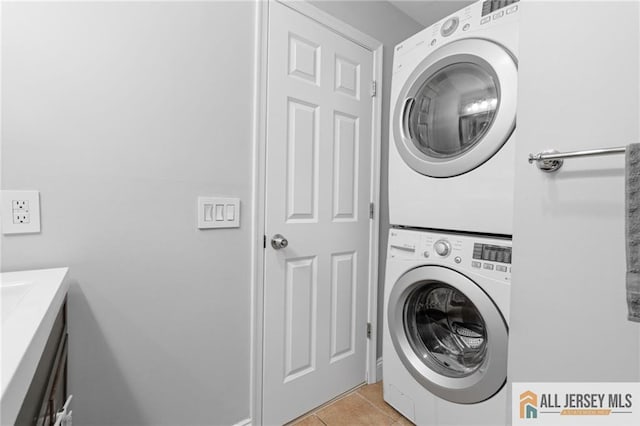 washroom featuring stacked washer / drying machine and light tile patterned floors