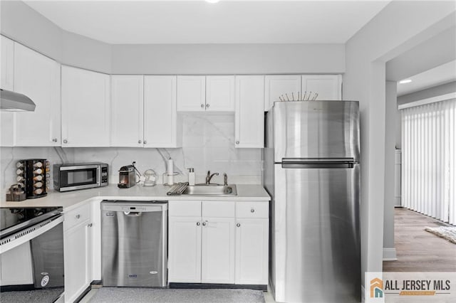 kitchen featuring stainless steel appliances, white cabinetry, sink, and decorative backsplash