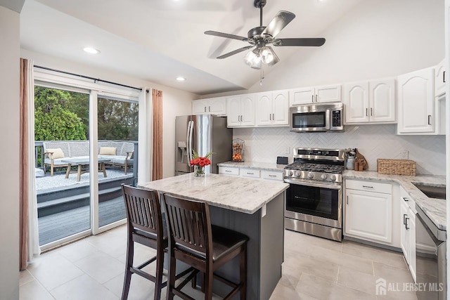 1 York St, Old Bridge, NJ 08857 - kitchen with appliances with stainless steel finishes, a kitchen breakfast bar, tasteful backsplash, ceiling fan, and light stone countertops