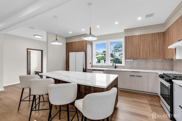 35 Glenville Rd, Edison, NJ 08817 - kitchen featuring gas range oven, freestanding refrigerator, a kitchen island, a breakfast bar area, and decorative backsplash