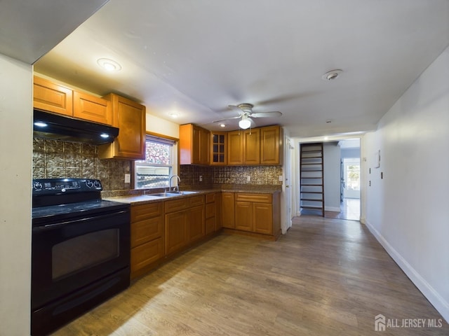 kitchen featuring ceiling fan, sink, black / electric stove, light hardwood / wood-style floors, and decorative backsplash