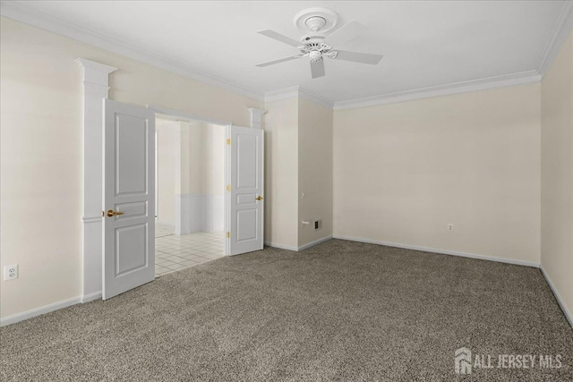 carpeted spare room with ceiling fan, baseboards, and crown molding