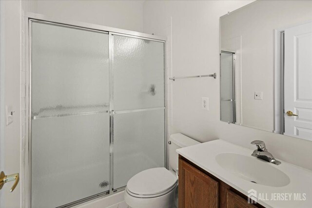 bathroom featuring vanity, a shower with door, and toilet