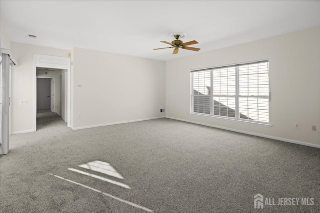 carpeted spare room with a ceiling fan, visible vents, and baseboards