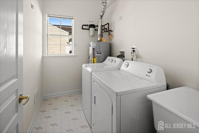 washroom featuring laundry area, baseboards, washer and clothes dryer, water heater, and a sink