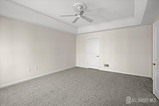 spare room with a tray ceiling, ornamental molding, ceiling fan, and carpet flooring