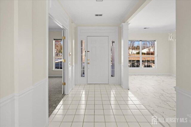 entryway featuring ornamental molding and decorative columns