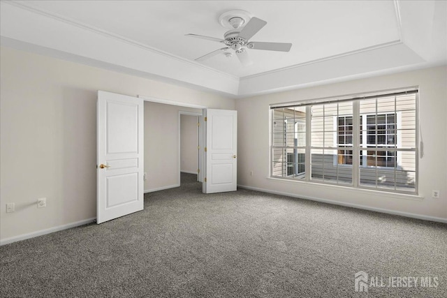 unfurnished bedroom with a tray ceiling, carpet, a ceiling fan, and baseboards