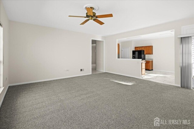 unfurnished living room featuring ceiling fan and light carpet