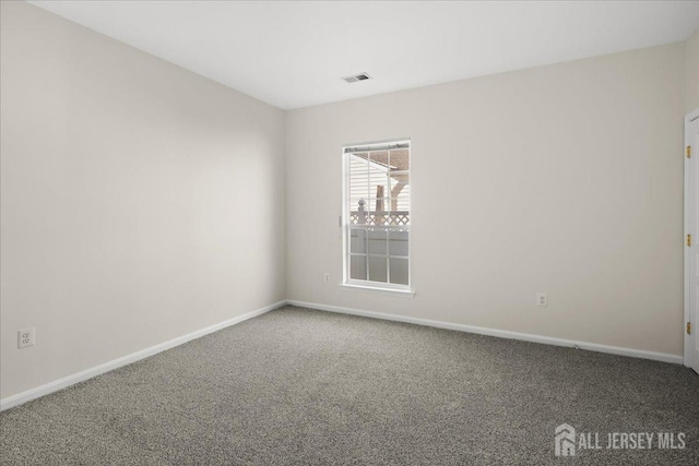 spare room with carpet floors, visible vents, and baseboards