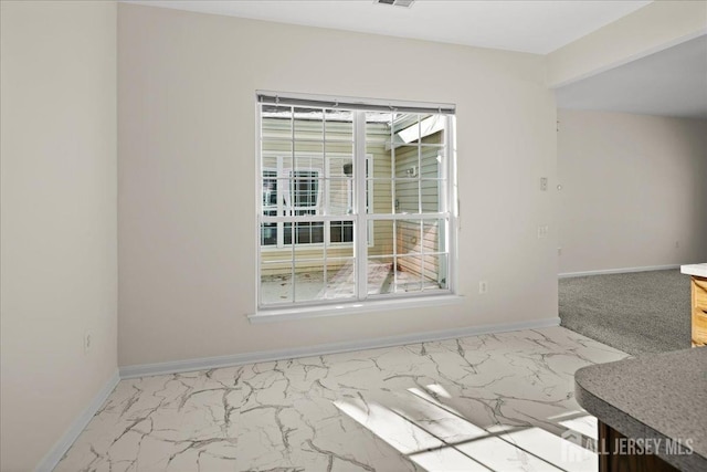 empty room featuring marble finish floor, visible vents, and baseboards