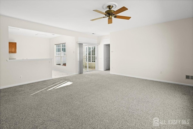 empty room with baseboards, visible vents, a ceiling fan, and light colored carpet