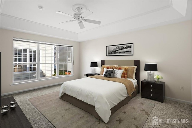 carpeted bedroom with ceiling fan and a tray ceiling