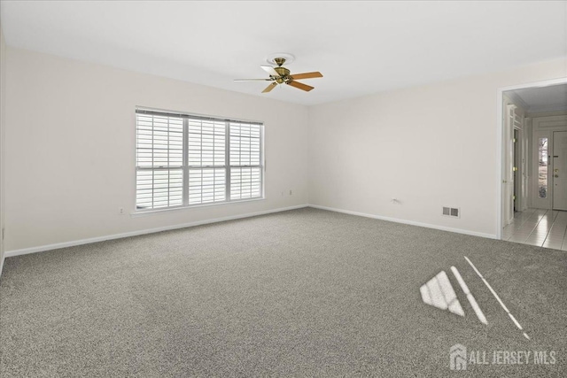 empty room with light carpet, baseboards, visible vents, and a ceiling fan