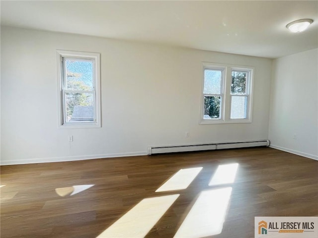 spare room featuring a baseboard radiator, a wealth of natural light, and wood finished floors