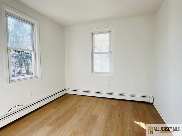 spare room featuring baseboard heating and wood finished floors