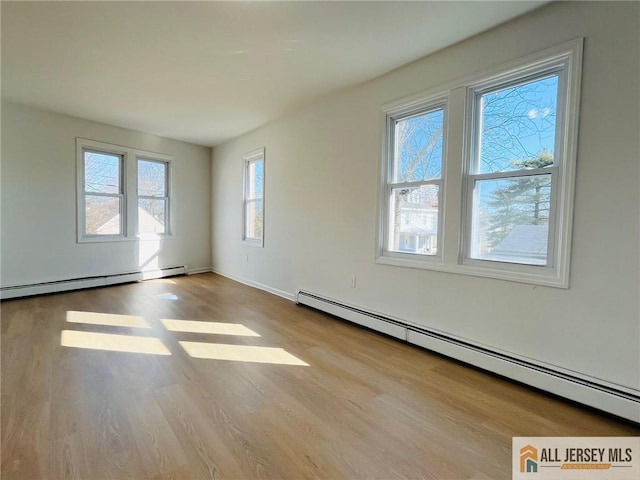 spare room featuring a baseboard radiator, baseboards, and wood finished floors