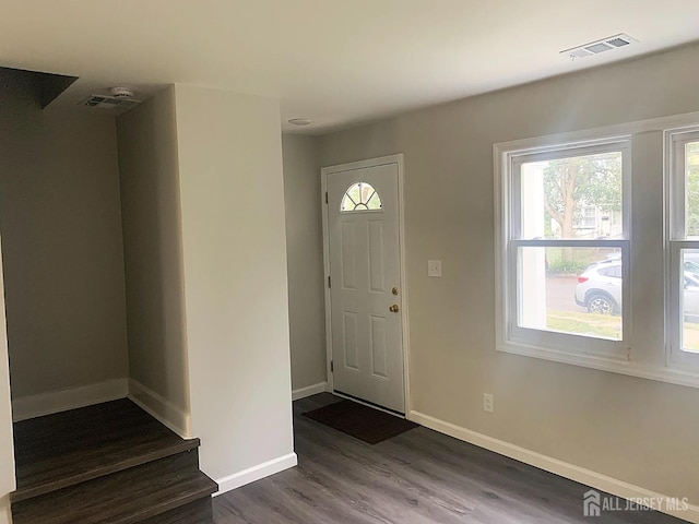 foyer entrance featuring visible vents, baseboards, and dark wood finished floors