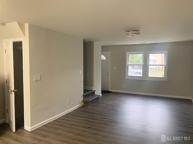 spare room featuring baseboards and dark wood-style floors