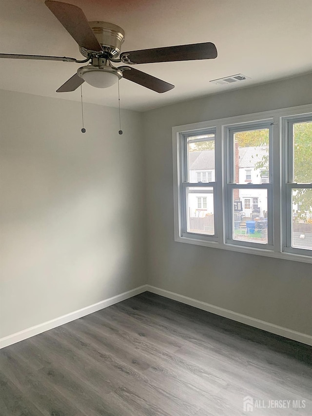 spare room featuring visible vents, baseboards, and dark wood finished floors