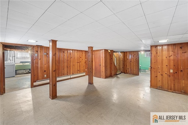 basement with a baseboard heating unit, washer / clothes dryer, sink, and wood walls