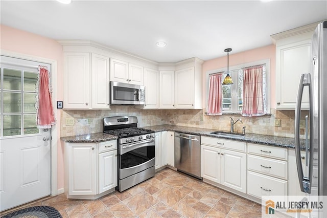 kitchen with appliances with stainless steel finishes, sink, hanging light fixtures, and white cabinetry