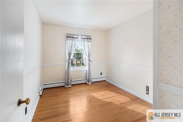 empty room with baseboard heating, crown molding, and hardwood / wood-style floors