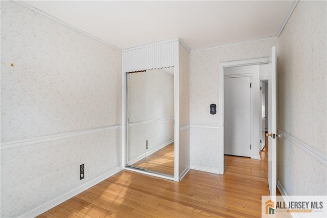 unfurnished bedroom with ornamental molding, hardwood / wood-style flooring, and a closet