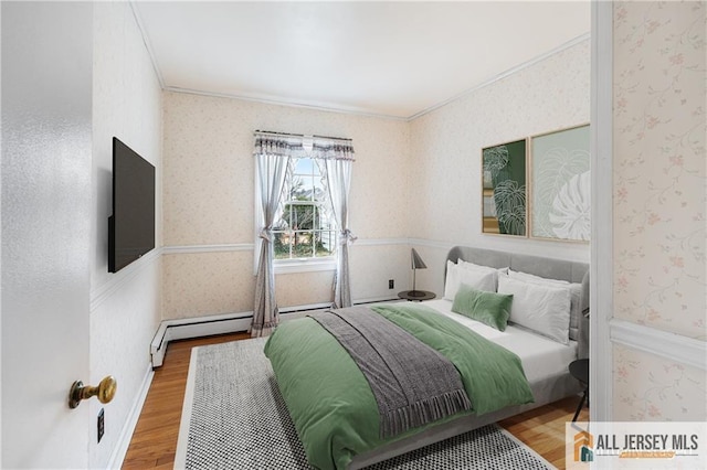 bedroom with baseboard heating, hardwood / wood-style flooring, and ornamental molding