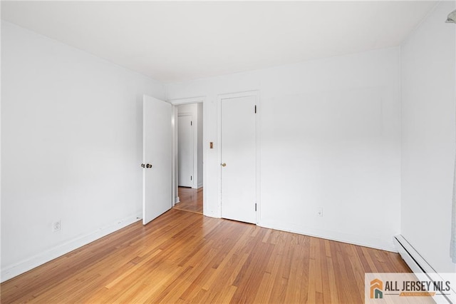 spare room with baseboard heating and light hardwood / wood-style floors