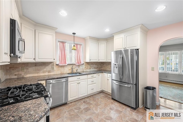 kitchen featuring a baseboard radiator, stainless steel appliances, dark stone counters, pendant lighting, and sink